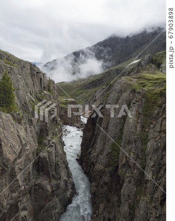View from footbridge over the wild Fernaubach mountain stream in Tyrol, Austria close to Mittelstation at Stubai. Summer foggy morning. 67903898