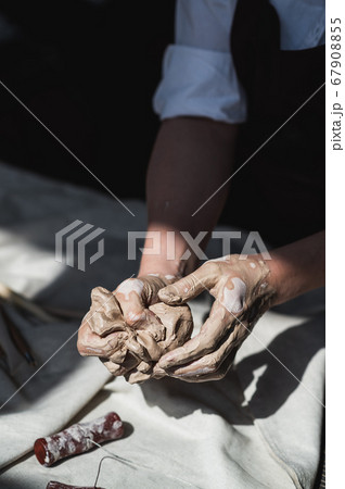 Close-up of a woman potter sculpts a brown clay pot on the background of a wooden table in the workshop 67908855