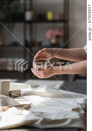 Close-up of a woman potter sculpts a brown clay pot on the background of a wooden table in the workshop Close-up of a woman potter sculpts a brown clay pot on the background of a wooden table in the workshop 67908857