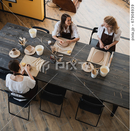 Caucasian female best friends pottery artists decorating a ceramic pod, talking and smiling during their work in arts studio. 67908939