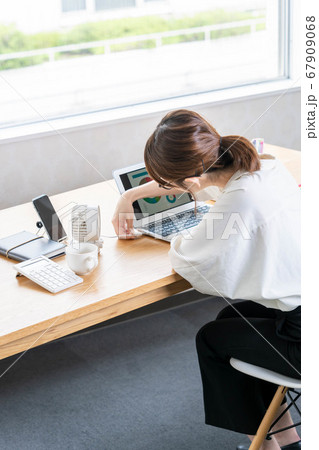 テレワーク中に卓上扇風機をセッティングする若い女性 【クールビズ】 67909068