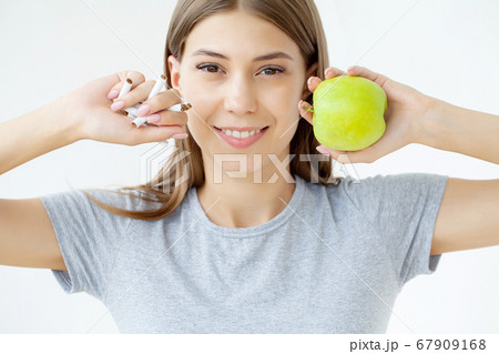 Stop smoking, woman holding a broken cigarette and a green apple Stop smoking, woman holding a broken cigarette and a green apple 67909168