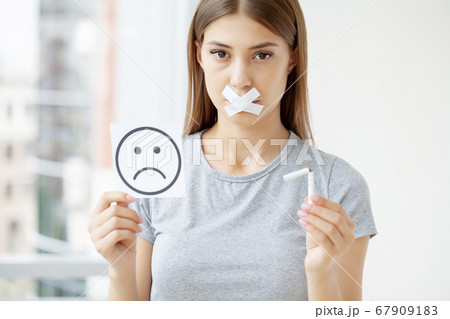 Stop smoking, a woman with a sealed mouth holding a broken cigarette 67909183