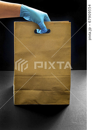 A person wearing gloves holding a shopping brown A person wearing gloves holding a shopping brown 67909554
