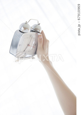 目覚まし時計を持つ手 67910969
