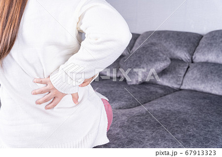 Young woman suffering from back pain while sitting 67913323