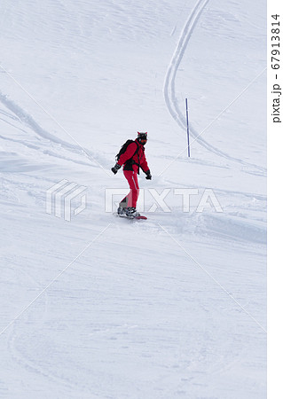 Snowboarder in red descends on snowy ski slope 67913814