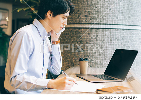 電話をしながらパソコンを見る男性 67914297