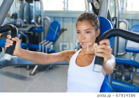 Gym workout Asian woman focused and motivated training on pec deck fly machine. Fitness workout 67914586