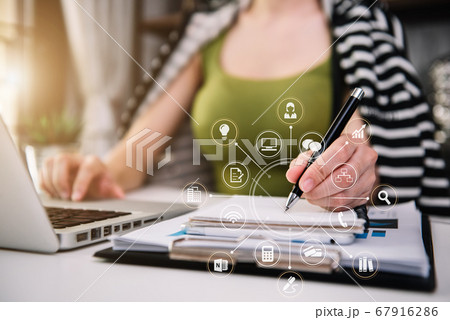 Female businessman use a laptop computer and take notes in the notebook at the home office desk in the morning. 67916286