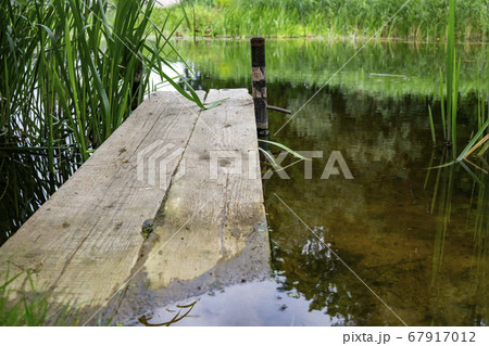 Old rustic wooden jetty on a tranquil lake 67917012