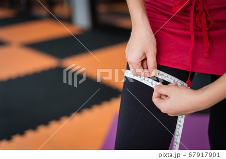 woman use measuring tape to measure her leg after exercise at gym, sport and health concept with copy space for text woman use measuring tape to measure her leg after exercise at gym, sport and health concept with copy space for text 67917901