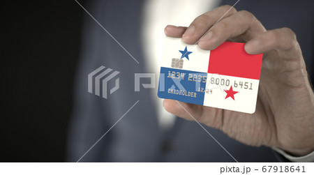 Businessman holding plastic bank card with printed flag of Panama in his hands, fictional numbers Businessman holding plastic bank card with printed flag of Panama in his hands, fictional numbers 67918641