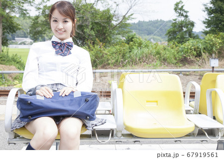 駅のホームのベンチに座る女子高校生 67919561