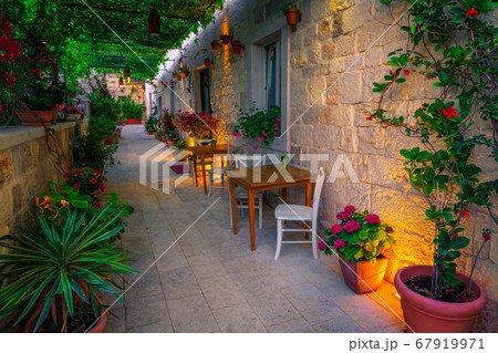 Harmonious narrow street and street cafe decorated with flowers Harmonious narrow street and street cafe decorated with flowers 67919971