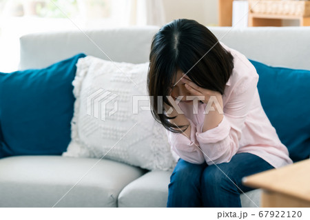 不安で顔を覆うミドル女性【リビング】 67922120