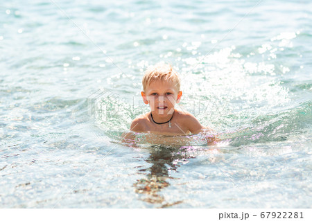 Happy little boy playing in the waves at the 67922281