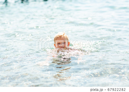 Happy little boy playing in the waves at the 67922282