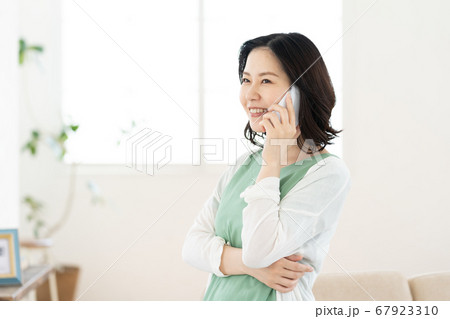 スマホで通話するミドル女性【リビング】 スマホで通話するミドル女性【リビング】 67923310