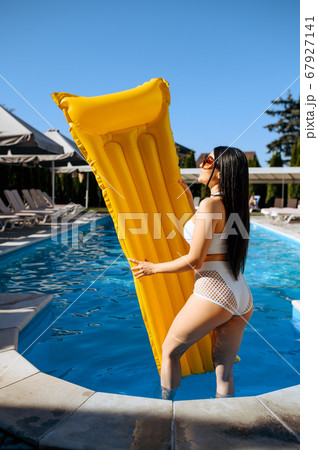 Slim woman with inflatable mattress at poolside Slim woman with inflatable mattress at poolside 67927141