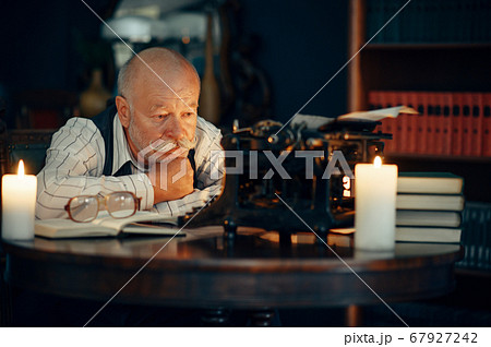 Adult writer works on typewriter with candle light Adult writer works on typewriter with candle light 67927242