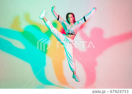 Young beautiful woman dancing hip-hop, street style isolated on studio background in neon light Young beautiful woman dancing hip-hop, street style isolated on studio background in neon light 67928753