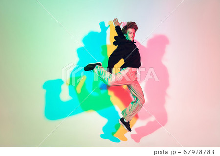 Young beautiful man dancing hip-hop, street style isolated on studio background in neon light 67928783