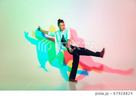 Young beautiful man dancing hip-hop, street style isolated on studio background in neon light Young beautiful man dancing hip-hop, street style isolated on studio background in neon light 67928824