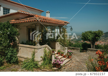 Old house with stairs leading to porch full of flowers at Monsanto 67932237