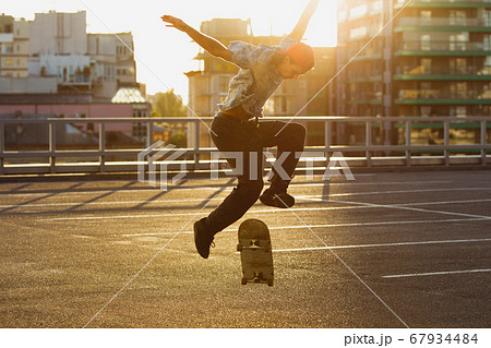Skateboarder doing a trick at the city's street in summer's sunshine 67934484