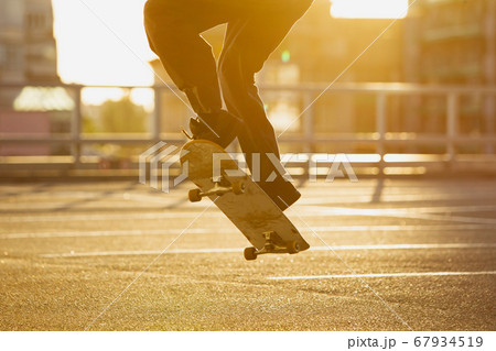 Skateboarder doing a trick at the city's street in summer's sunshine Skateboarder doing a trick at the city's street in summer's sunshine 67934519