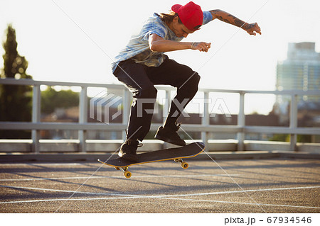 Skateboarder doing a trick at the city's street in summer's sunshine 67934546