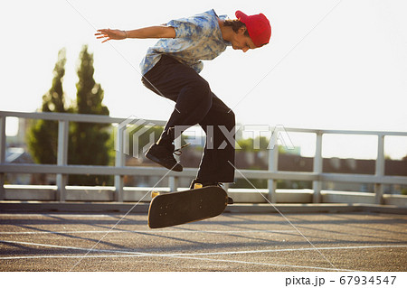 Skateboarder doing a trick at the city's street in summer's sunshine 67934547