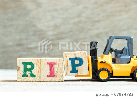 Toy forklift hold letter block P to complete word RIP (abbreviation of rest in peace) on wood background 67934732