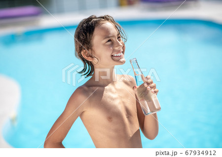 Happy boy with bottle of water by pool 67934912