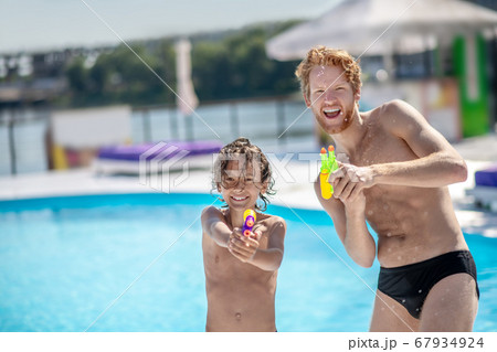Wet and funny dad with son with water gun Wet and funny dad with son with water gun 67934924