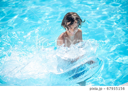 Boy with power vigorously moving hands in water. 67935156