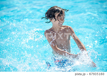 Energetic boy standing in water making splashes 67935160