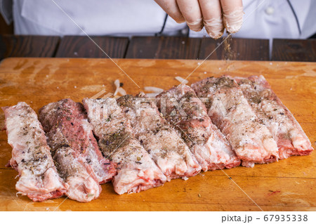 Preparation and cooking of pork ribs by a chef for a grill. 67935338