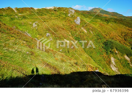 飯豊山の稜線に立つ登山者の影 67936396