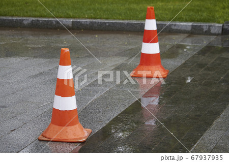 Side view of two bright orange-white warning cones Side view of two bright orange-white warning cones 67937935