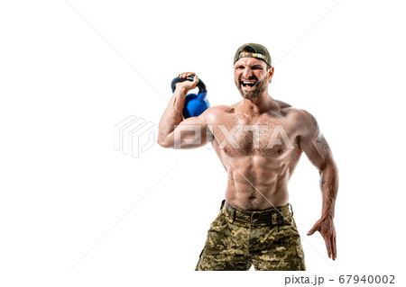 Muscular athlete bodybuilder man in camouflage pants with a naked torso workout with kettlebell on a white background. 67940002