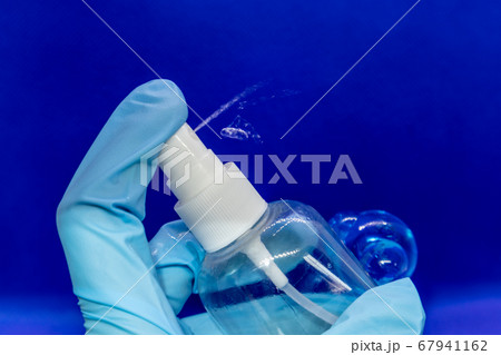 Spray disinfect liquid, hand in blue glove on blue Spray disinfect liquid, hand in blue glove on blue 67941162