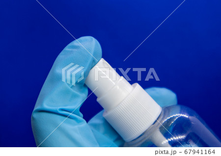 Spray disinfect liquid, hand in blue glove on blue Spray disinfect liquid, hand in blue glove on blue 67941164