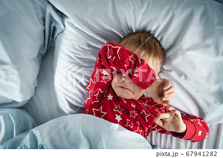 Sleepy boy lying in bed with blue beddings 67941282