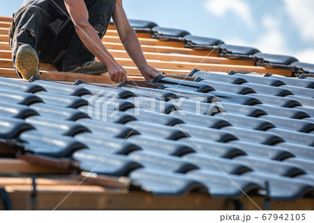 The roof coverer laying a new roof on the new building, bungalow, construction concept 67942105