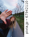 Beautiful blond girl climbed out of car window, looks and catches wind 67942110