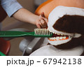 Crop kid cleaning teeth of toy 67942138