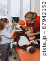 Little girl and dentist checking teeth of toy 67942152
