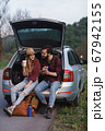 Couple sit on the trunk of car and wonder at photo on tablet 67942155